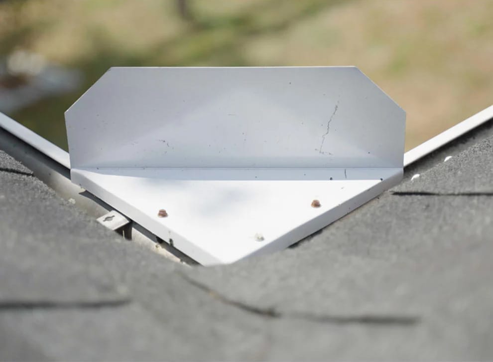 A metal roof flashing is installed at the intersection of two shingle roof sections, secured with screws. A metal roof flashing is installed at the intersection of two shingle roof sections, secured with screws.