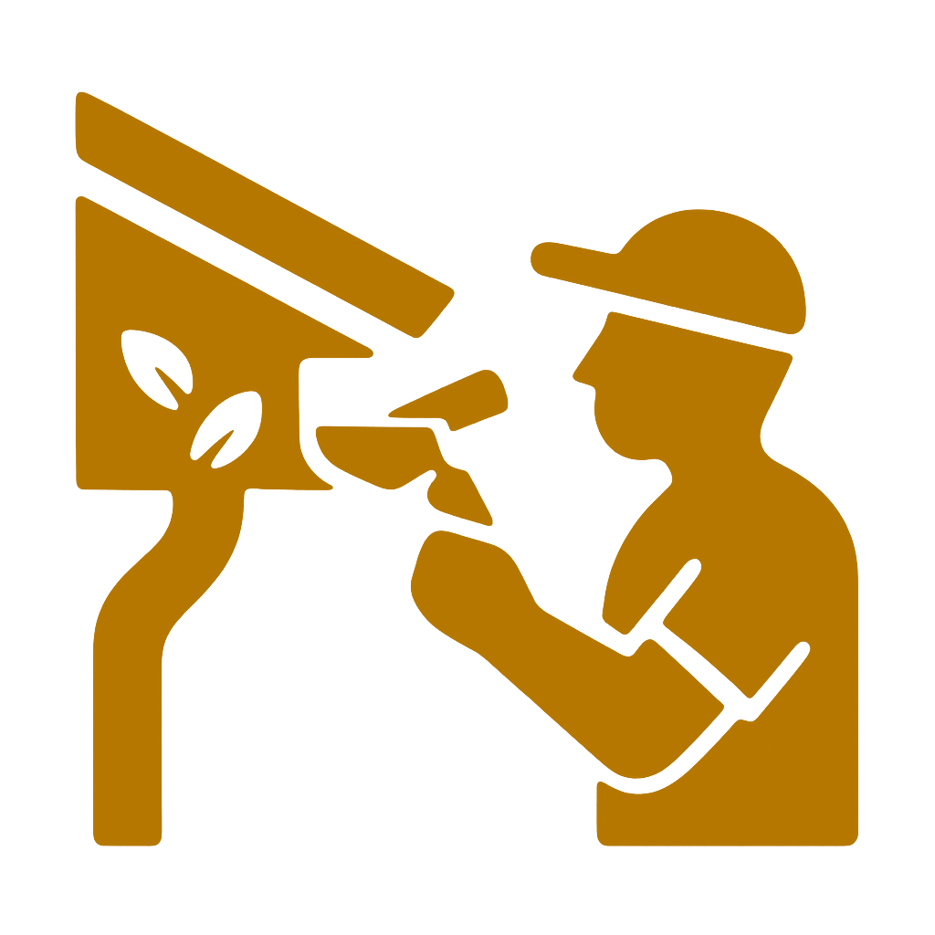 A person wearing a cap paints a wooden birdhouse mounted on a pole using a paint roller.